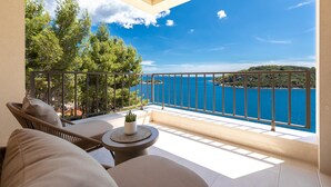 Un balcón con vista al mar, una planta en maceta y mobiliario exterior.
