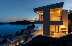 Une maison moderne à deux étages dotée d’un balcon donnant sur un plan d’eau.