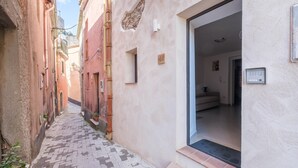 A narrow alleyway with buildings on either side, a door with a number plate, and a small window. - Holiday Home 'Casa Mark' with Sea View, Wi-Fi and Air Conditioning (Forza d'Agrò)