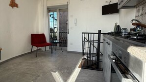 A modern kitchen with a stainless steel range, a red chair, and a view through an open door to a balcony. - Holiday Home 'Casa Mark' with Sea View, Wi-Fi and Air Conditioning (Forza d'Agrò)