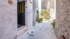 A narrow alleyway with a building entrance, a door, and a potted plant. - Holiday Home 'Casa Mark' with Sea View, Wi-Fi and Air Conditioning (Forza d'Agrò)