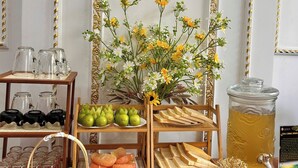 Una mesa de madera con una variedad de alimentos, como frutas, pan y bebidas, dispuesta para un bufé.