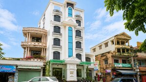 A hotel with a prominent central tower, multiple balconies, and a green awning. - Collection O Queen Hotel Central Hue (Hue)