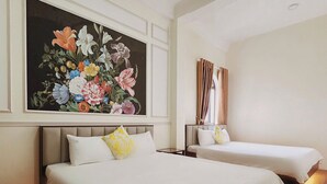 Una habitación de hotel con dos camas, un cuadro grande con motivos florales en la pared y suelo de madera.