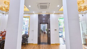Un hall de hotel con piso de mármol, columnas decoradas y una araña.