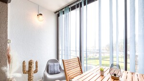 Una habitación con una mesa de madera, una decoración de cactus, una silla, una planta en maceta y un aplique de pared.