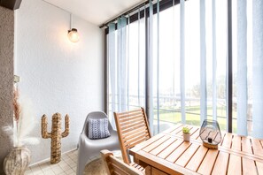 A room with a wooden table, a cactus decoration, a chair, a potted plant, and a wall-mounted light fixture. - bellevue apartment – on the port terrace and wifi (La Grande-Motte)