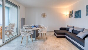 Una sala de estar moderna con un sofá, una mesa de comedor con sillas, un reloj de pared y obras de arte.