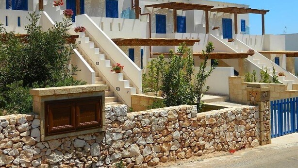 Un immeuble à plusieurs étages avec des murs blancs, des volets bleus et des escaliers en pierre.
