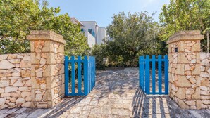 Un mur de pierre avec une porte bleue donnant sur un chemin pavé.