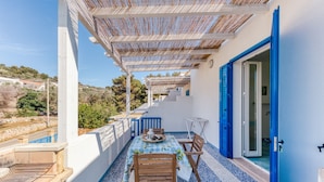 Un balcon avec une table et des chaises, une porte bleue et une vue sur le paysage environnant.