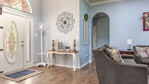 Una sala de estar con un sofá gris, una consola blanca y un adorno de pared.