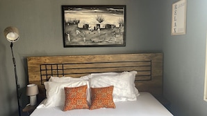 A bedroom with a wooden headboard, white bedding, and two patterned pillows. - Cozy Bricks Apartment (Obomeng)