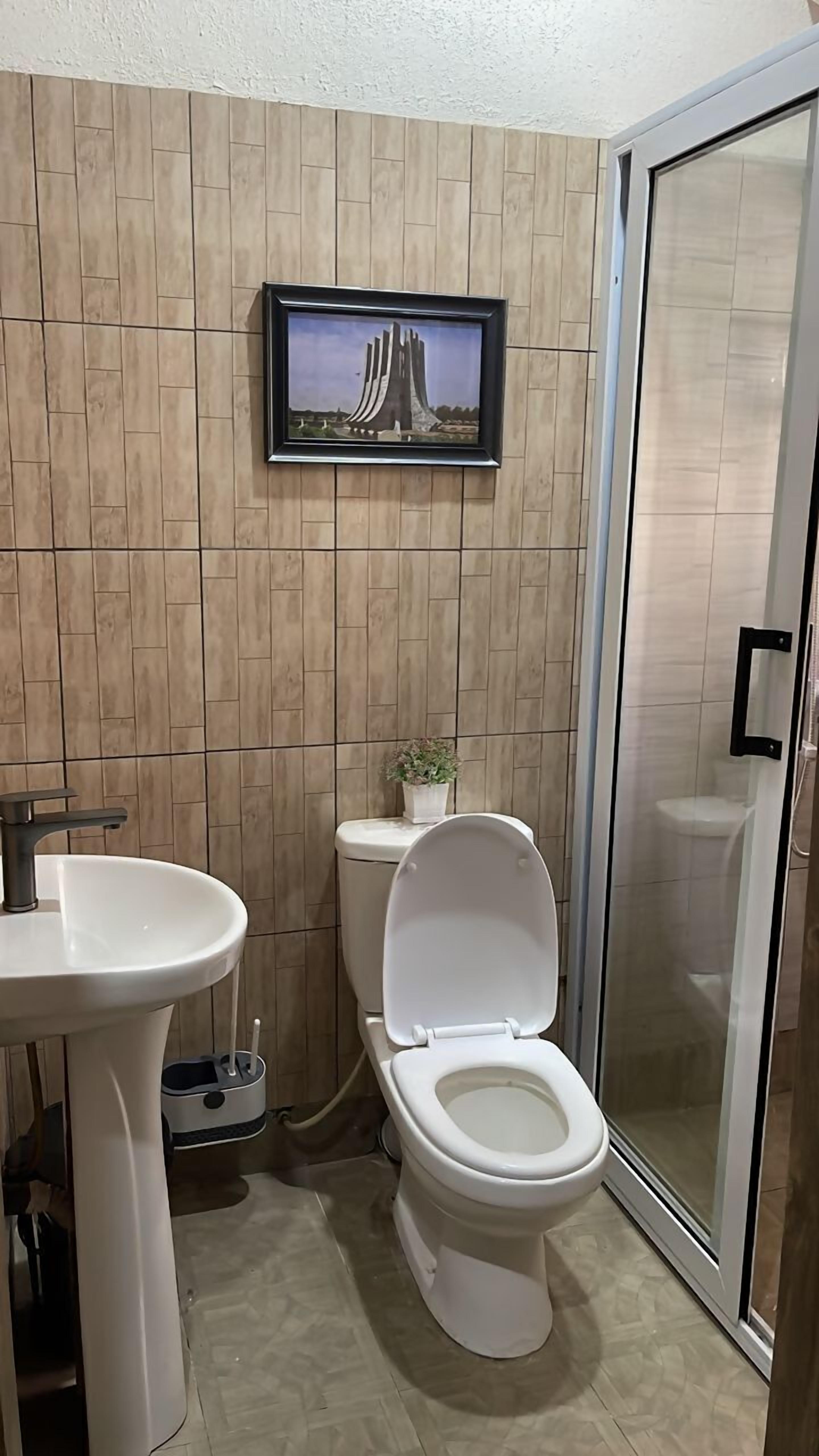 Ein Badezimmer mit modernem Design, das Toilette, Waschbecken und eine Duschfläche umfasst.