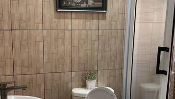Ein Badezimmer mit modernem Design, das Toilette, Waschbecken und eine Duschfläche umfasst.