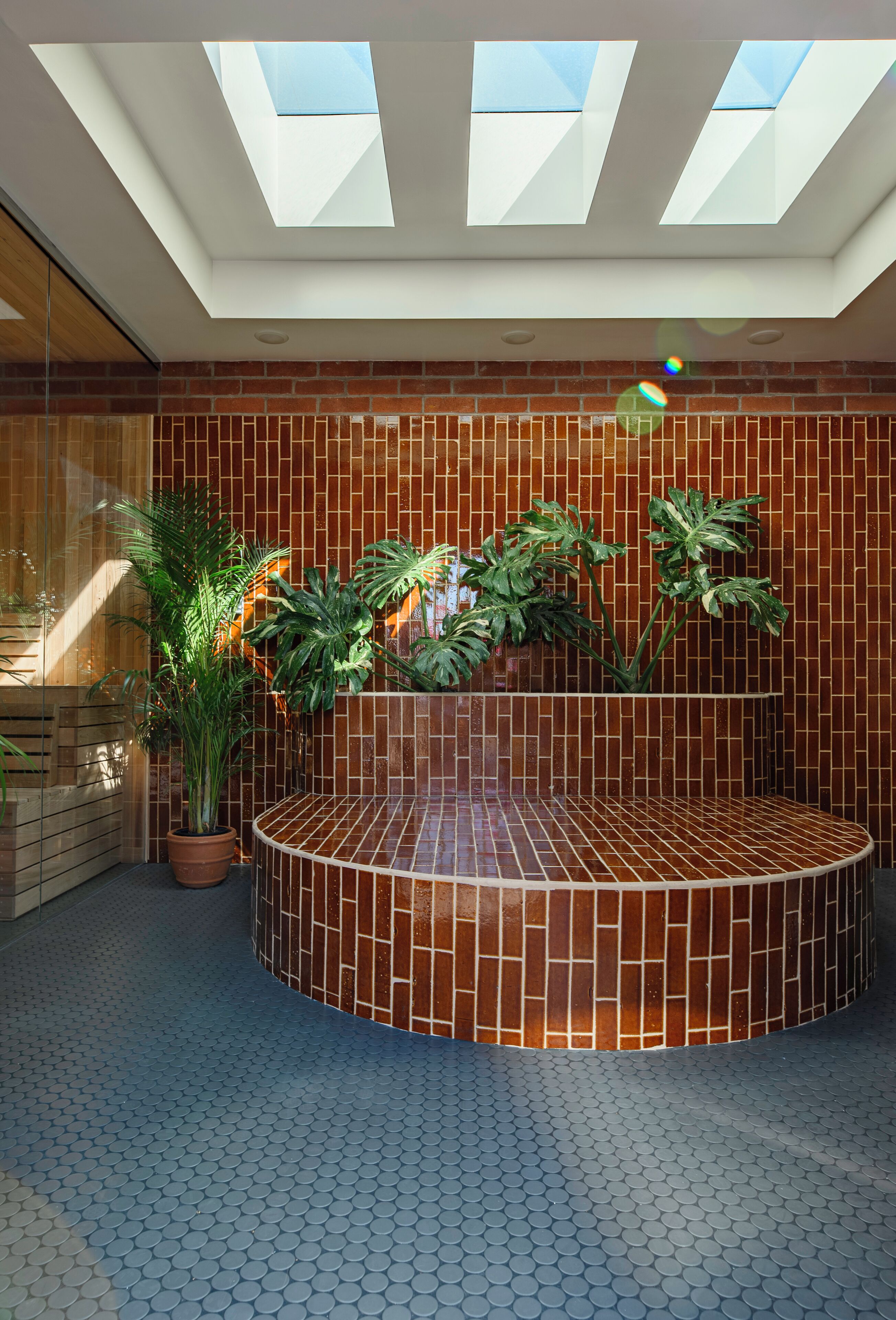 Um interior moderno com uma área de estar circular, uma parede de tijolos e um claraboia.