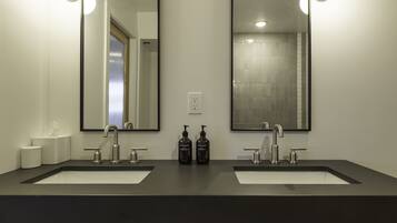 A modern bathroom with two sinks, a large mirror, and two bottles of hand soap.