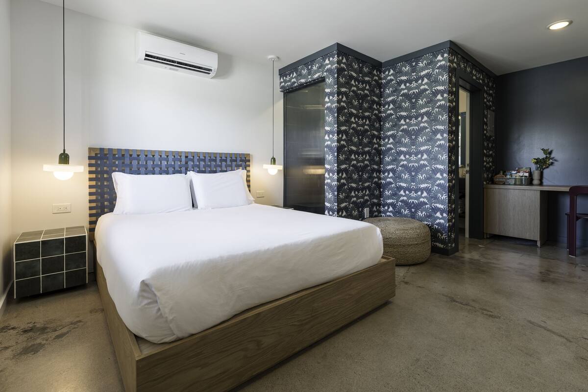 A modern bedroom with a large bed, a built-in desk, and a walk-in closet.