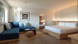 A modern hotel room with a large bed, a sofa, a small table, and a mirror. - Best Bet Motor Lodge  (Reno)