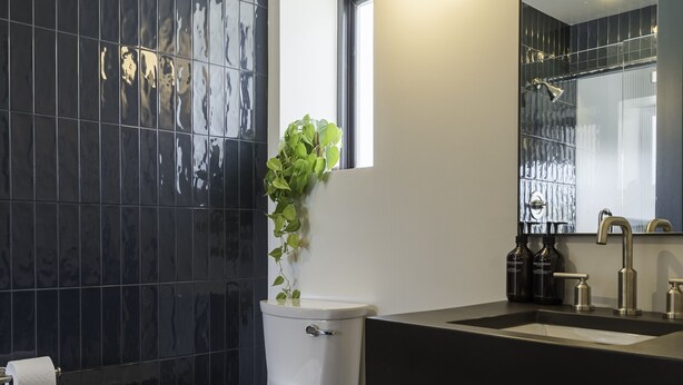 A modern bathroom with a toilet, sink, and mirror. - Best Bet Motor Lodge  (Reno)