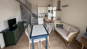 Un ambiente compatto con angolo ristoro, angolo cottura e una scala.