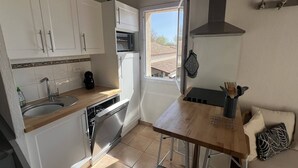 Una cucina compatta con mobili bianchi, forno integrato, lavastoviglie e una finestra che offre luce naturale.