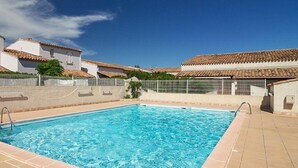 Una piscina rettangolare con bordo piastrellato, circondata da un muretto e una recinzione.