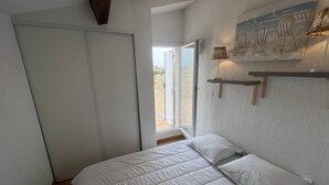 Una camera da letto con un letto, una porta scorrevole, una finestra e una mensola a parete con oggetti decorativi.