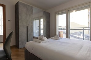 Ett modernt hotellrum med en stor säng, en inbyggd garderob och stora fönster med utsikt över staden.