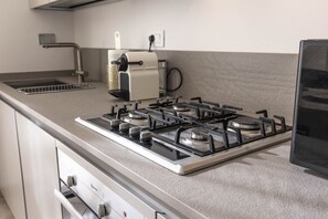 A kitchen with a gas stove, a coffee maker, and a dishwasher.