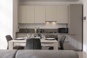 A modern kitchen with light-colored cabinets, a dining table set with plates and glasses, and a microwave on the countertop.