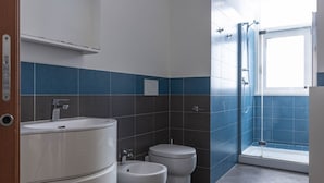 Un baño moderno con lavamanos, bidé, inodoro y ducha.