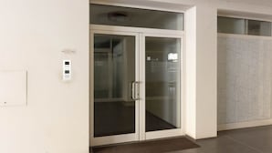 Un interior moderno con puerta de cristal, un interruptor de luz en la pared y un revestimiento mural estampado.