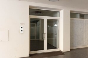 En modern inredning med en entré som har en glasdörr, en väggmonterad ljusströmbrytare och en vägg med ett mönster.