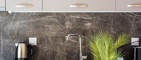 A modern kitchen with marble backsplash, stainless steel appliances, and wooden cabinetry.