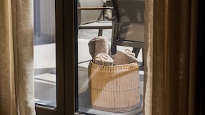 A sliding glass door leading to an outdoor seating area with a woven basket containing towels. - Stone and Sea Villas (Lefkada)