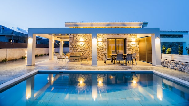 A modern outdoor pool area with stone walls, outdoor furniture, and a clear pool. - Stone and Sea Villas (Lefkada)