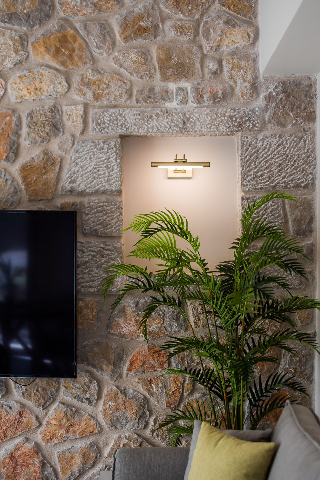 A stone wall with a flat-screen TV mounted on it.