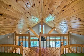 An attic room with wooden beams, a window, and a view of the outdoors.