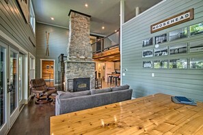 A spacious living area with a stone fireplace, a wooden dining table, and a cozy seating arrangement.