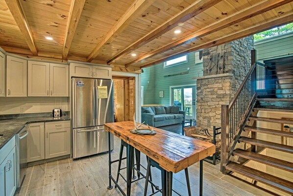 A kitchen with wooden beams, a stone fireplace, and a wooden staircase.