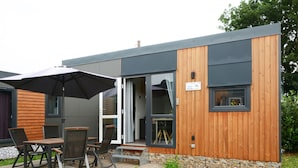 A modern building with a wooden deck, outdoor seating, and a sign indicating the house number 76. - Tiny Haus Central by Interhome (Beilngries)