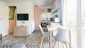 A modern kitchen with a dining area, a TV, and a window with a view. - Tiny Haus Eder by Interhome (Beilngries)