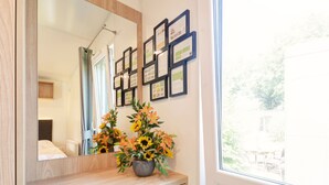 A bathroom with a wooden vanity, a mirror, framed certificates on the wall, and a window with a view of greenery. - Tiny Haus Eder by Interhome (Beilngries)