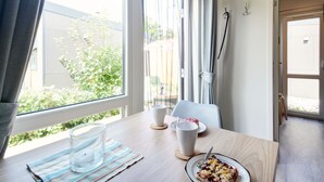 A room with a wooden table, a glass of water, a plate with food, and a window with curtains. - Tiny Haus Eder by Interhome (Beilngries)