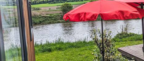 A riverside view with red umbrellas and a wooden deck.