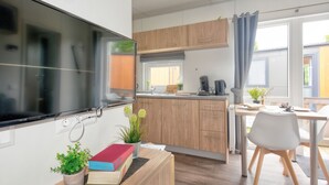 Et moderne køkken med træskabe, komfur indbygget i skabet, samt et spiseområde med bord og stole.