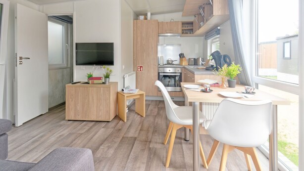 Et moderne køkken med træskabe, ovn og spiseplads med bord og stole.