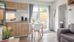 Et moderne køkken med træskabe, et spiseområde med et bord og stole, samt en grå sofa.