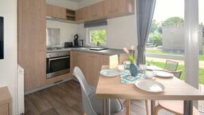 Eine moderne Küche mit Holzschränken, einem eingebauten Ofen und einer Essecke mit Tisch für zwei Personen.